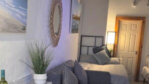 Un dormitorio con cama, planta en maceta, espejo y puerta.