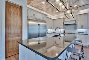 A modern kitchen with a large island, stainless steel appliances, and a wooden door. - Private Pool/Free Bikes! 0.7 Miles from Beach. (Santa Rosa Beach)