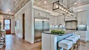 Una cocina moderna con una isla central, electrodomésticos de acero inoxidable y techo de madera.