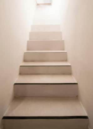 Eine enge, weiße Treppe mit einem Teppich-Belag.