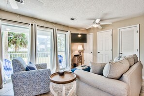 A living room with a sofa, armchair, and a small table. There is a ceiling fan, a TV, and a lamp on a side table. - Pet Friendly! Seagrove 30A! 1st Floor. Pool/Tennis! (Santa Rosa Beach)