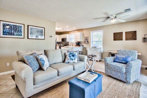A living room with a sofa, a patterned armchair, and a coffee table. There is a kitchen in the background with white cabinets and a microwave. - Pet Friendly! Seagrove 30A! 1st Floor. Pool/Tennis! (Santa Rosa Beach)