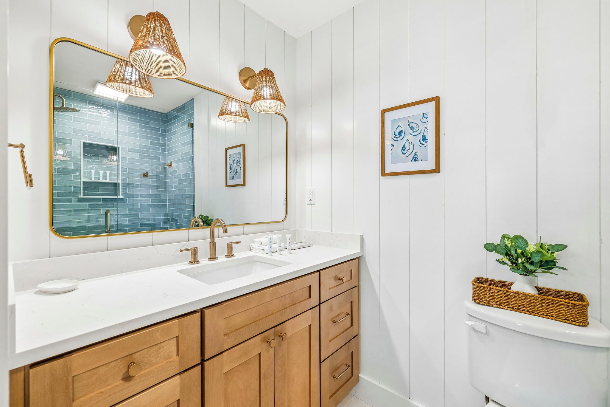 A bathroom with a white vanity, a large mirror, and a wall-mounted sink.