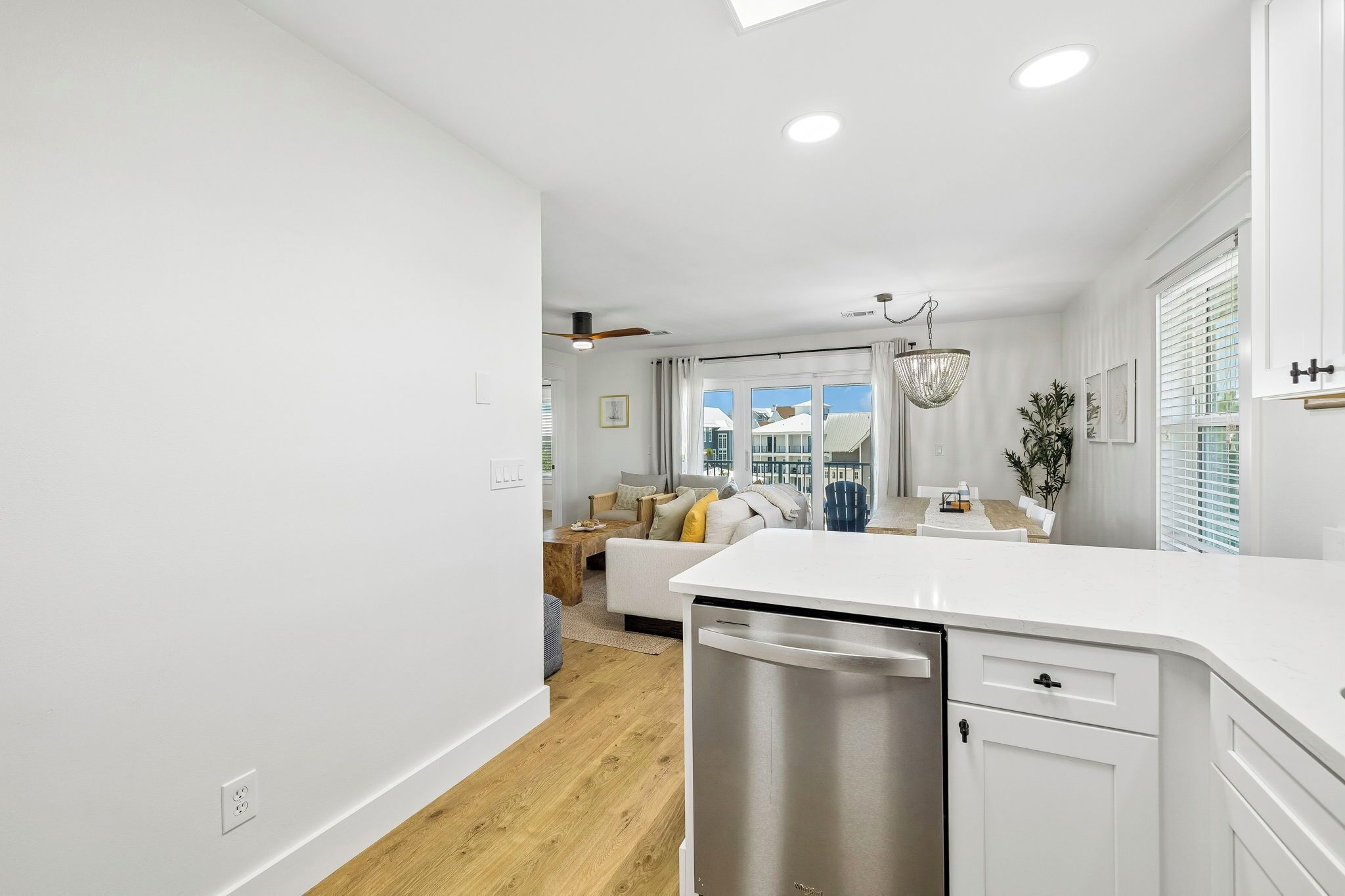 A modern kitchen with a dishwasher, a dining area with a table and chairs, and a living room with a sofa and a coffee table.