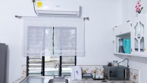 A kitchen with a sink, a microwave, and a window with a white curtain. - La Casona Blanca (San Marcos)