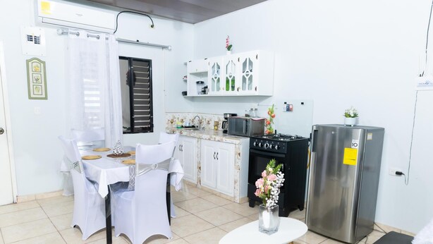 A kitchen with white cabinets, a stove, a refrigerator, and a dining table with chairs. - La Casona Blanca (San Marcos)