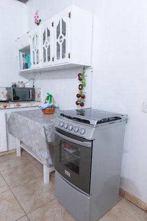 A kitchen with a stove, oven, microwave, and white cabinets.