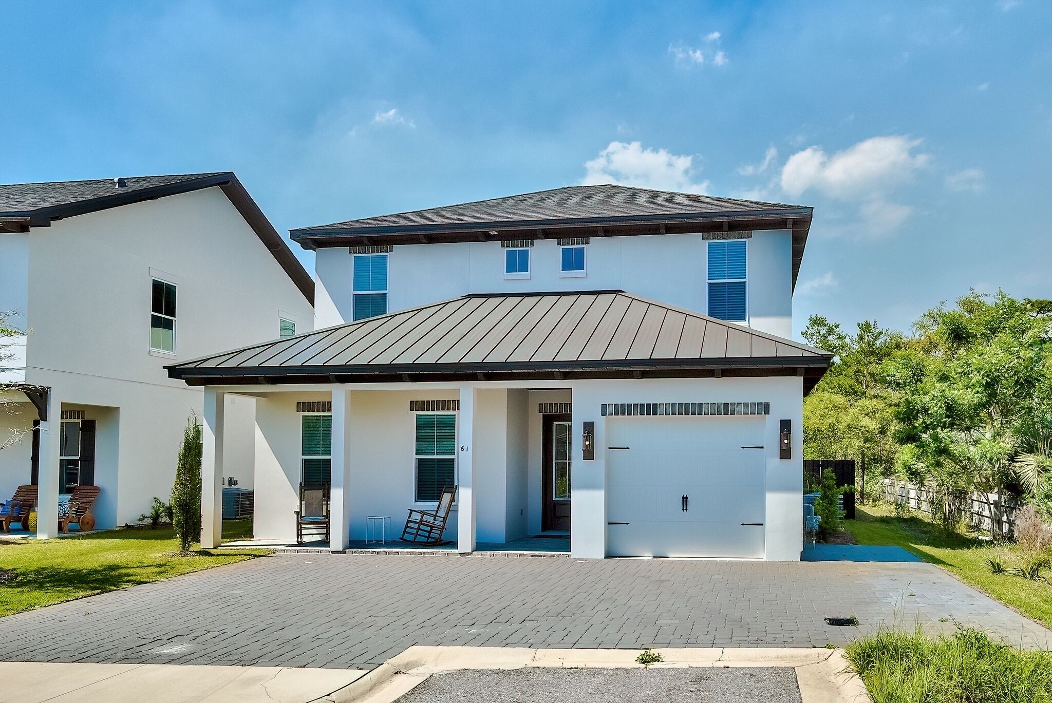 A modern two-story house with a garage, a covered porch, and a well-maintained lawn.