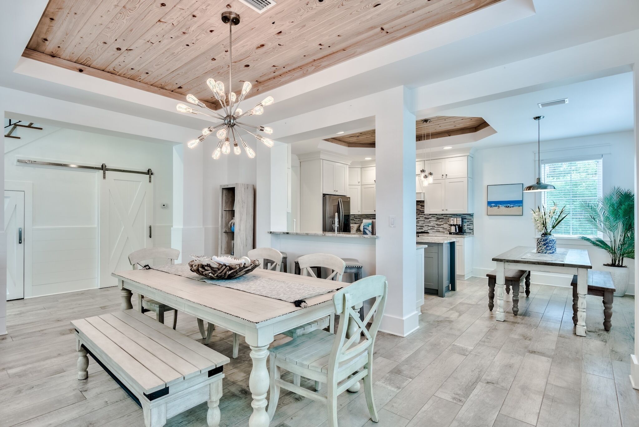 Un'ampia cucina con mobili bianchi, un'isola centrale e un'area pranzo con tavolo e panche in legno.