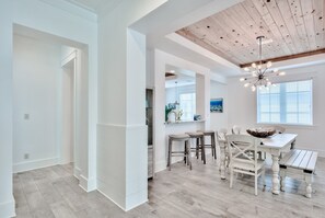A spacious kitchen with a wooden ceiling, a dining area with a white table and chairs, and a large window with blinds. - 30A Family House! Free Bikes. Walk to Coffee/Dinner! (Santa Rosa Beach)