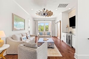 Ein modernes Wohnzimmer mit Sofa, Sessel, Couchtisch und einem Bild an der Wand.