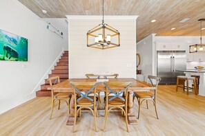 Eine moderne Küche mit einem Edelstahl-Kühlschrank, Holzschränken und einem Essbereich mit Holztisch und Stühlen.