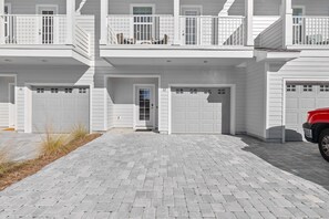 A two-story house with a front garage, a balcony with outdoor furniture, and a paved driveway. - Quiet Street SRB! Less than 5 minutes to Beach! (Santa Rosa Beach,)
