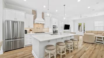 A modern kitchen with white cabinetry, stainless steel appliances, and a central island with stools.