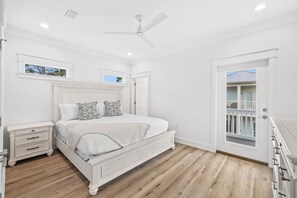 A bedroom with a white bed, a nightstand, a ceiling fan, and a door leading to a balcony. - Private Pool/Golf Cart! Bikes. 5 minute walk to Beach! (Santa Rosa Beach)