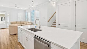 Una cocina moderna con una isla central, armarios blancos y un lavavajillas de acero inoxidable.