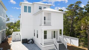 A two-story white building with a balcony, a covered porch, and a paved driveway.