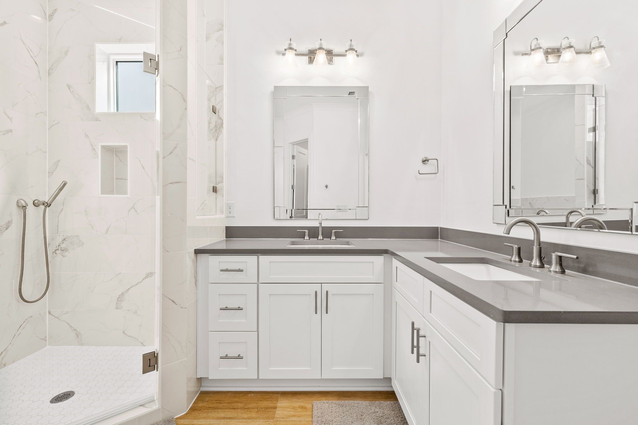 Een moderne badkamer met een douche, een wastafel en een grote spiegel.