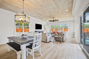 A spacious living area with a dining table, sofa, and TV. - Quiet Street. 0.6 miles from beach. Private Pool/Grill/Bikes. (Santa Rosa Beach)