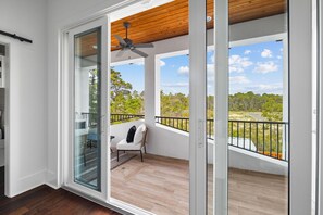 A balcony with a ceiling fan, a chair, and a view of a green landscape. - Quiet Street. 0.6 miles from beach. Private Pool/Grill/Bikes. (Santa Rosa Beach)