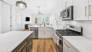 A modern kitchen with white cabinetry, stainless steel appliances, and a marble countertop. - Dune Allen/30A! Access to Pool, walk to Beach/Stinky's! (Santa Rosa Beach)