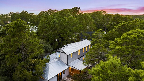 A two-story house surrounded by dense trees, with a visible deck and outdoor seating area. - Golf Cart/Bikes! Dune Allen/Walk to beach! (Santa Rosa Beach)