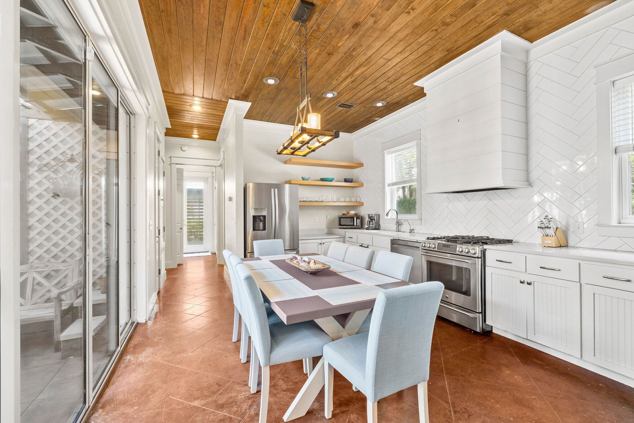A modern kitchen with white cabinetry, a central island, and a dining area with a large table and chairs.