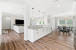 A modern kitchen with white cabinetry, a granite countertop, and pendant lighting. - Pet Friendly! Golf Cart/Bikes! Ride to Beach/Resort Pool! (Santa Rosa Beach)