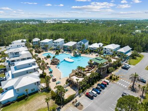 A resort with a central swimming pool, multiple buildings, and a parking area. - Pet Friendly! Golf Cart/Bikes! Ride to Beach/Resort Pool! (Santa Rosa Beach)