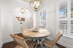 Un coin repas comprenant une table ronde, des chaises en bois, un lustre et un élément décoratif fixé au mur.