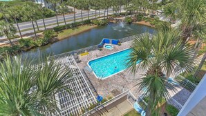 A pool with a water slide, surrounded by palm trees and a view of the ocean. - Gulf Place 30A! Walk to Beach. (SANTA ROSA BEACH)