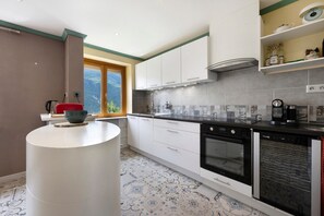 Una cocina moderna con armarios blancos, encimera negra y suelo estampado.