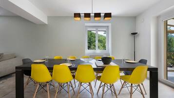 A modern dining area with a rectangular table, yellow chairs, and a central light fixture.