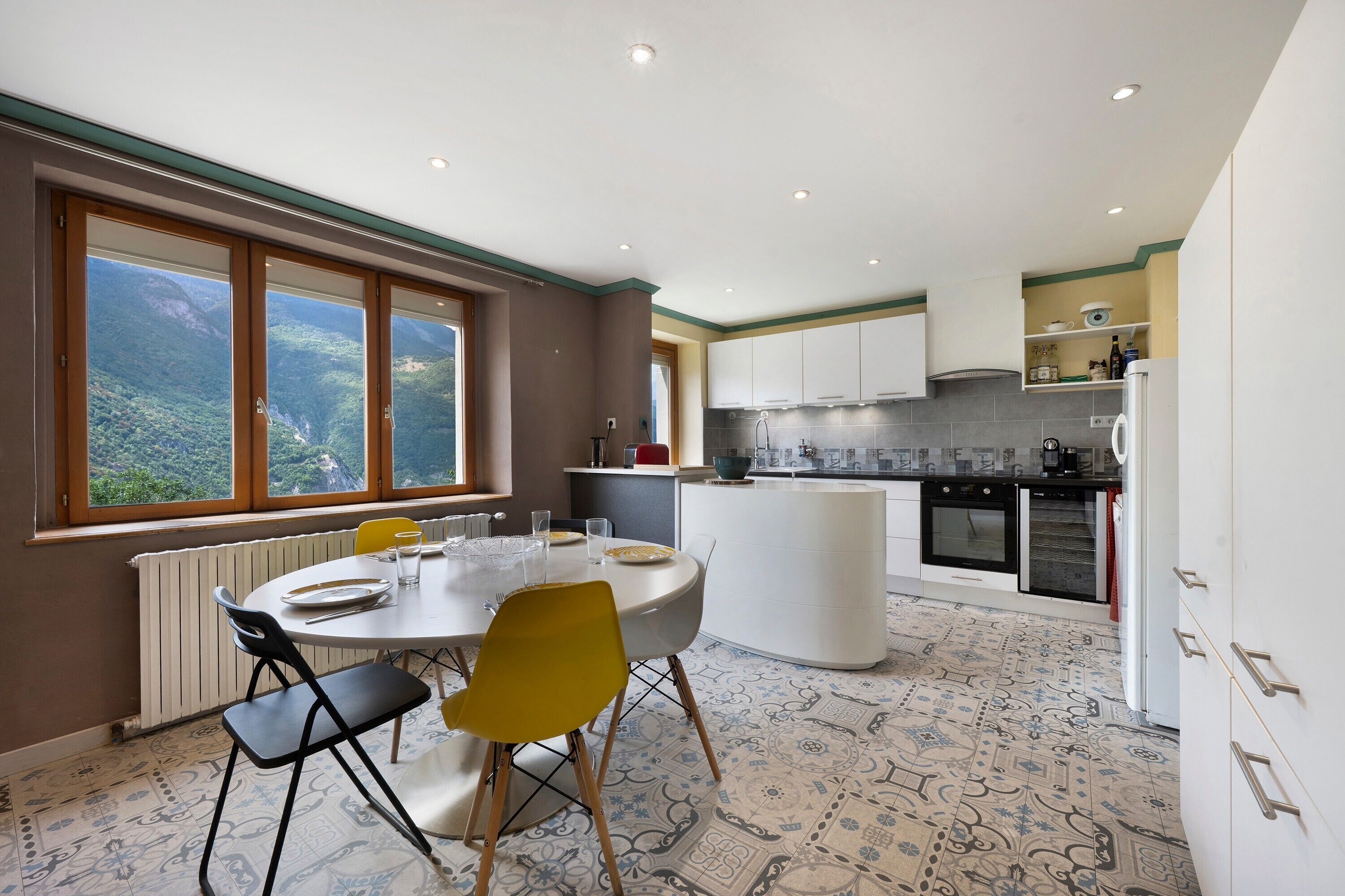 Una cucina moderna con mobili bianchi, forno integrato e zona pranzo con tavolo e sedie.
