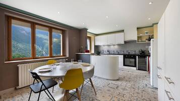 Una cucina moderna con mobili bianchi, forno integrato e zona pranzo con tavolo e sedie.
