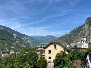 A mountain village with traditional architecture, a church, and a valley view.