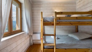 A bunk bed room with a window, curtains, and a wall-mounted air conditioner.