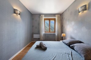 Un dormitorio con una cama, una ventana, una lámpara de pared y un radiador.