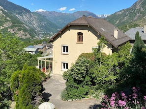Une maison avec un toit en pente, une fenêtre bien visible et un jardin où poussent différentes plantes et fleurs.