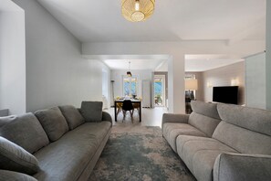 Una sala moderna con un conjunto de sofás, un comedor con sillas y un televisor.