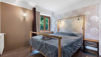 A bedroom with a bed, a window, a radiator, and a wooden floor.