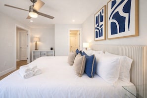 Een hotelkamer met een bed, een plafondventilator en kunst aan de muur.
