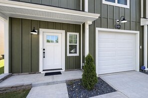 A residential house with a front door, garage, and a small tree in the front yard. - Modern Luxe 3BR Townhome Near Downtown Spartanburg (Spartanburg)