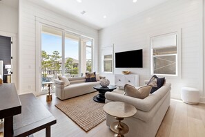 A modern living room with a sectional sofa, a coffee table, and a flat-screen TV mounted on the wall. - Brand New! 30A! Private Pool. Free Bikes. (Santa Rosa Beach)