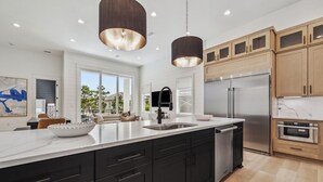 Une cuisine moderne dotée d’un grand îlot central, d’appareils électroménagers en acier inoxydable et d’armoires en bois.