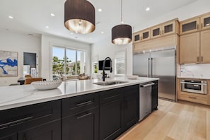 A modern kitchen with a large island, stainless steel appliances, and wooden cabinets. - Brand New! 30A! Private Pool. Free Bikes. (Santa Rosa Beach)