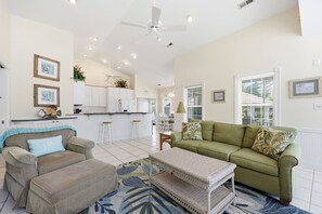 A spacious living area with a sofa, a coffee table, and a dining area in the background. - Match Point | Private Pool, Screened Porch, 3 Bedrooms (Emerald Isle)