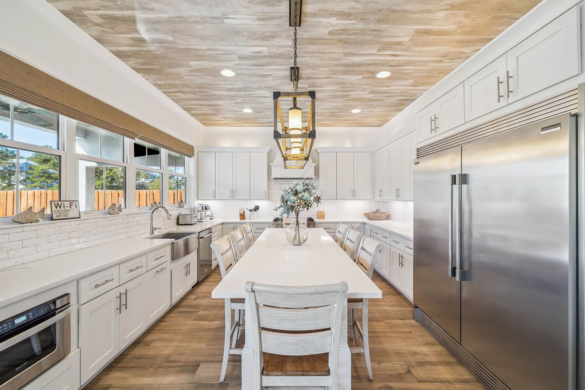 A modern kitchen with white cabinetry, a stainless steel refrigerator, and a central island with seating.