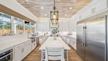 A modern kitchen with white cabinetry, a stainless steel refrigerator, and a central island with seating.