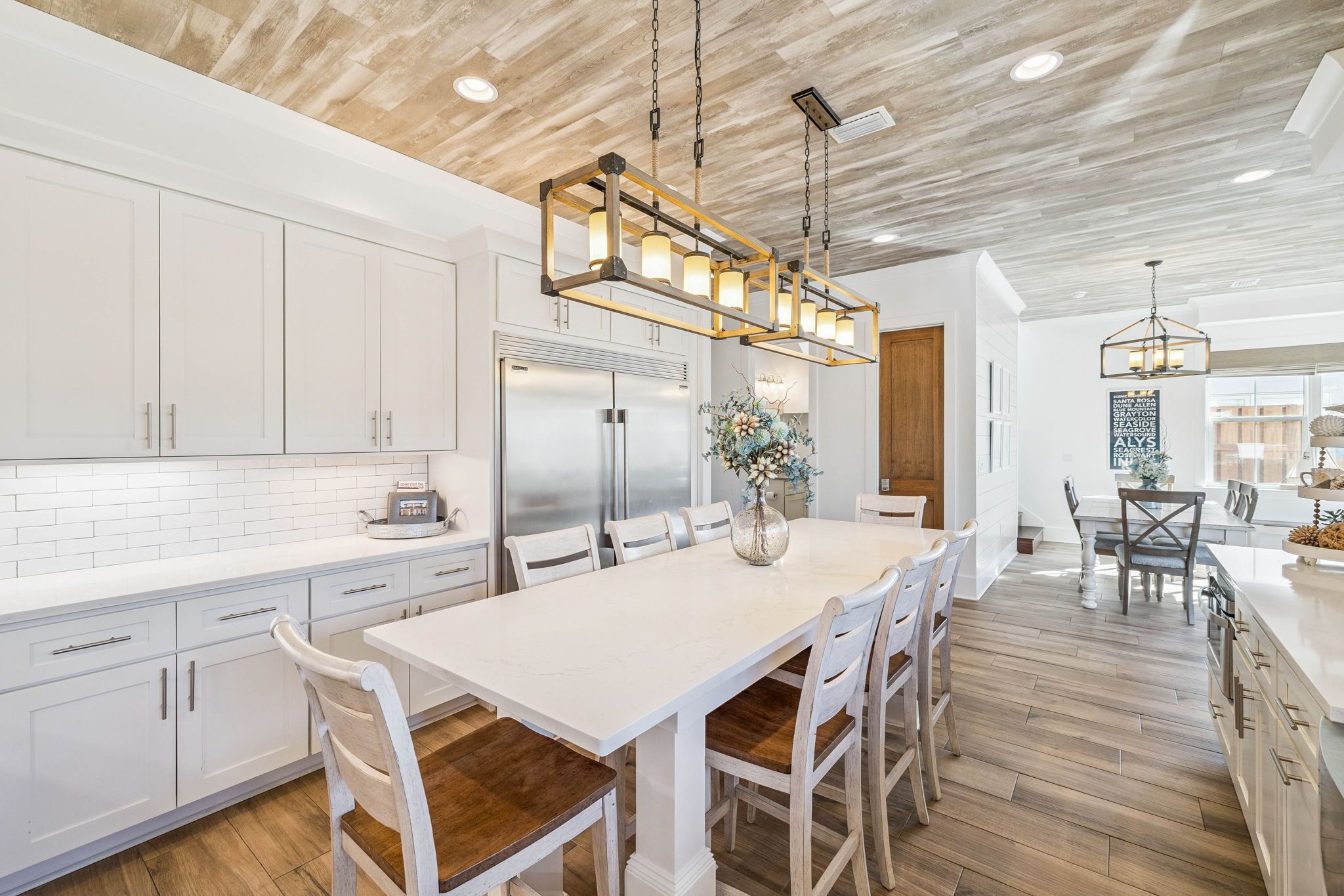 A modern kitchen with white cabinetry, a central island, and a hanging light fixture.